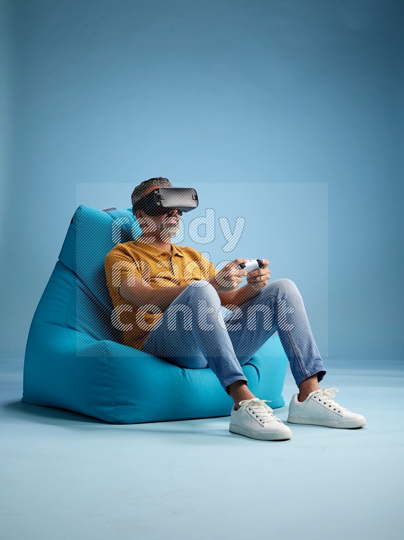 A man sitting on a blue beanbag and gaming with VR