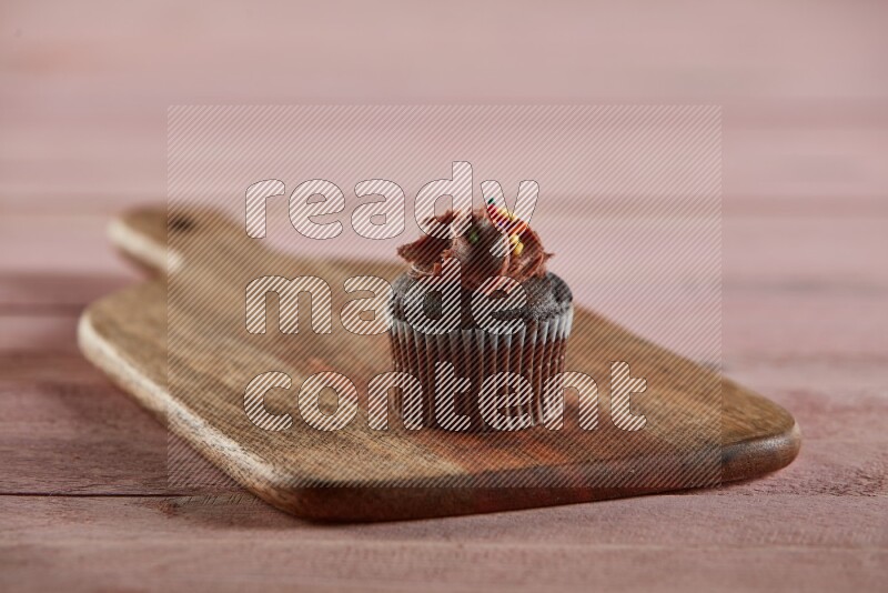 Chocolate mini cupcake topped with chocolate cream on a wooden board