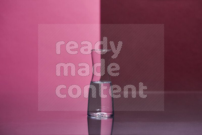 The image features a clear glassware filled with water, set against pink and dark red background