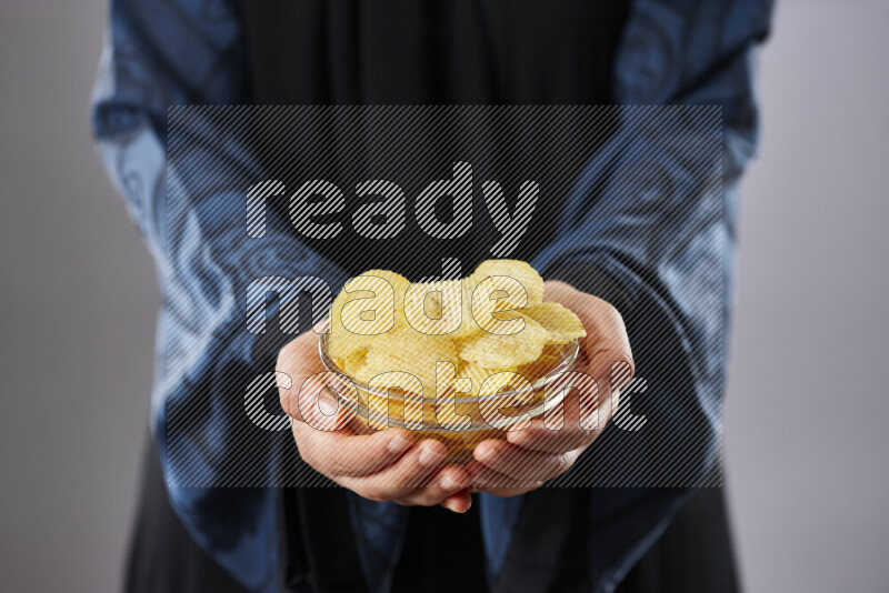 Woman in abaya holding different kinds of snacks in different positions