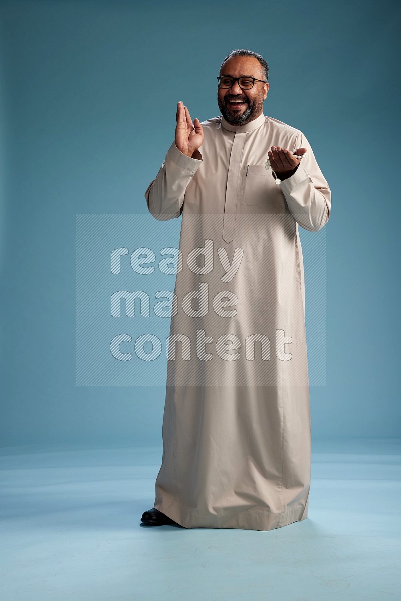 Saudi Man without shimag Standing Interacting with the camera on blue background