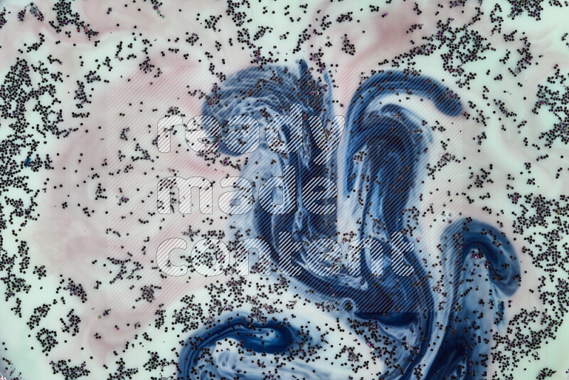 A close-up of sparkling purple glitter scattered on swirling green, red and blue background