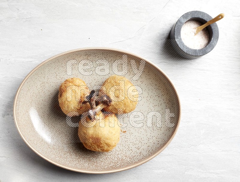 breaded drumstick on oval beige pottery plate on grey textured countertop