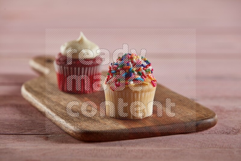 Vanilla mini cupcake topped with sprinkles on a wooden board