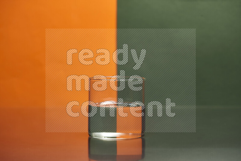 The image features a clear glassware filled with water, set against orange and dark green background