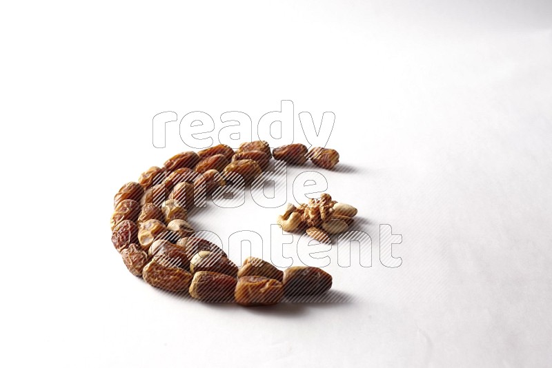 Dates in a crescent shape with nuts on white background