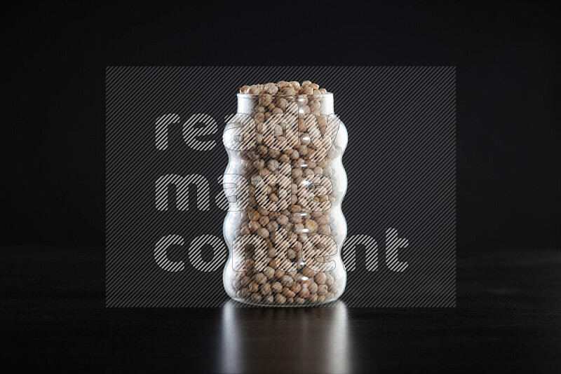 Chickpeas in a glass jar on black background