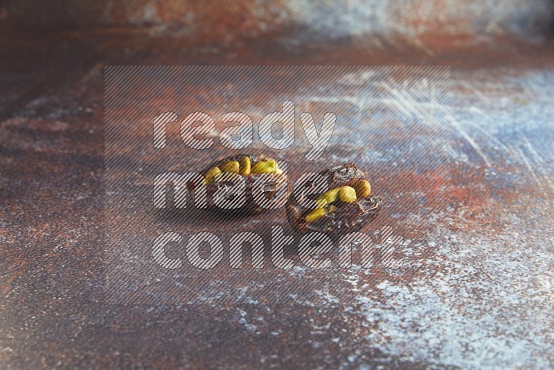 two pistachio stuffed madjoul dates on a rustic reddish background