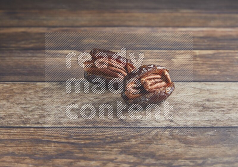 two pecan stuffed madjoul date on a wooden background
