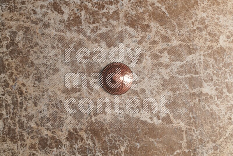A small copper pot on beige marble background