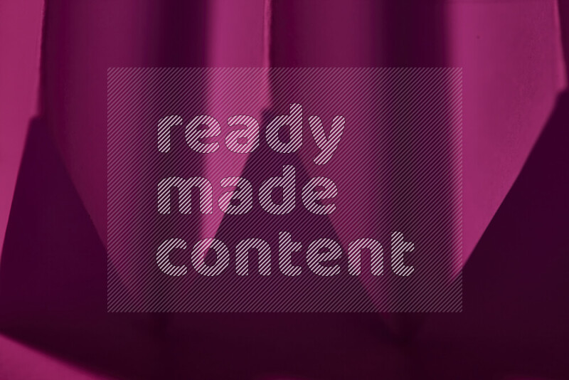 صورة مجردة مقربة تظهر طيات ورقية هندسية حادة بتدرجات اللون الوردي