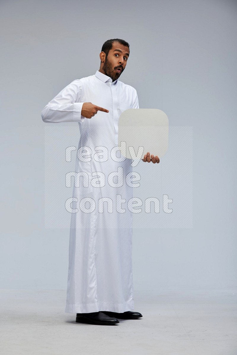 Saudi man wearing Thob standing holding social media sign on Gray background