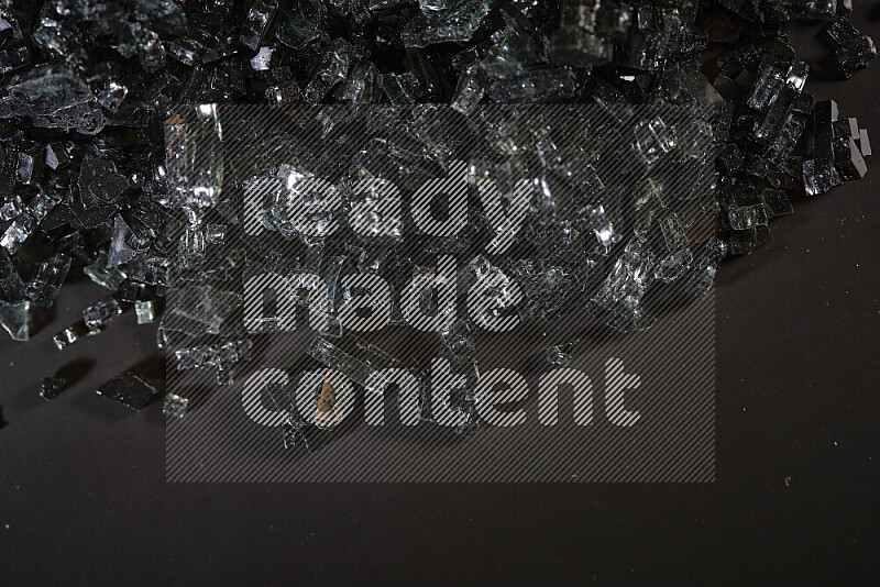Transparent black fragments of glass scattered on a black background