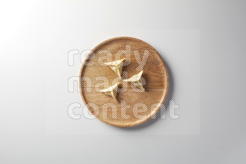 Three Sambosas on a wooden round plate on a white background