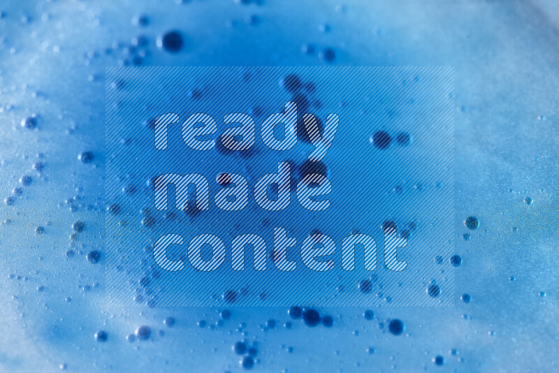 Close-ups of abstract blue watercolor drops on oil Surface on blue background