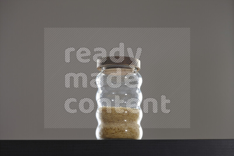 Basmati golden rice in a glass jar on black background