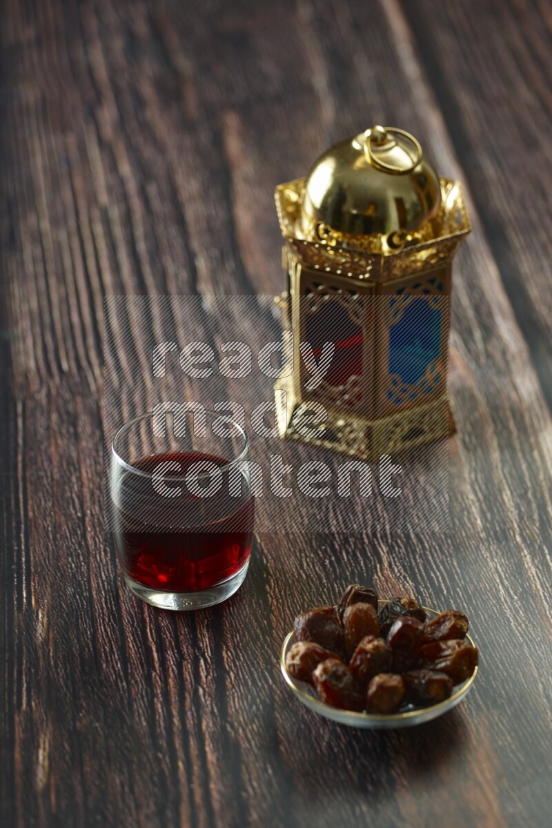 A golden lantern with different drinks, dates, nuts, prayer beads and quran on brown wooden background