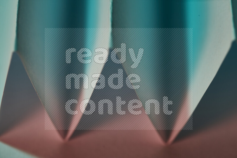 A close-up abstract image showing sharp geometric paper folds in green and red gradients