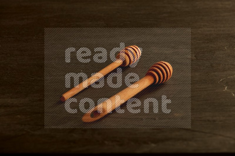 Wooden honey dipper on black slate background