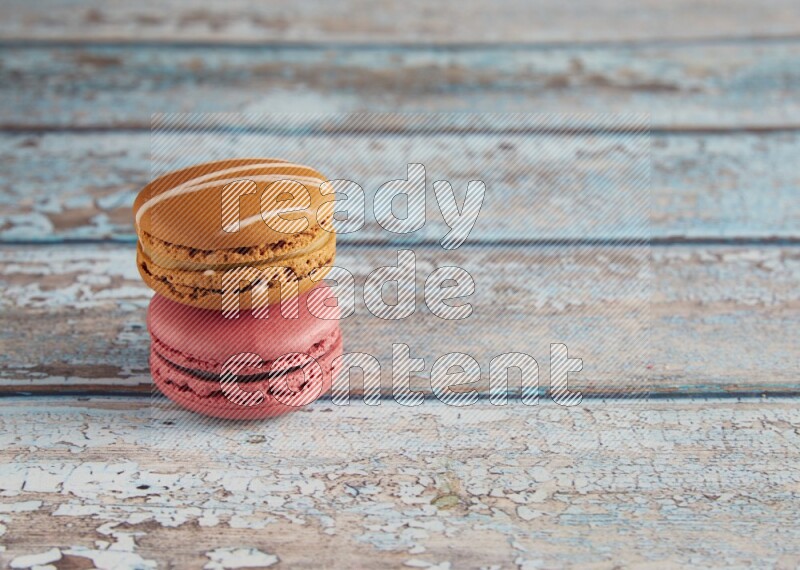 45º Shot of of two assorted Brown Irish Cream, and Pink Raspberry macarons on light blue background