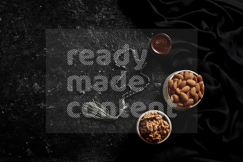 Nuts in pottery bowls with coffee in a dark setup