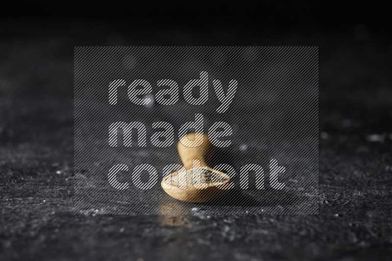 ملعقة خشبية مليئة ببودرة الفلفل الأبيض على أرضية سوداء