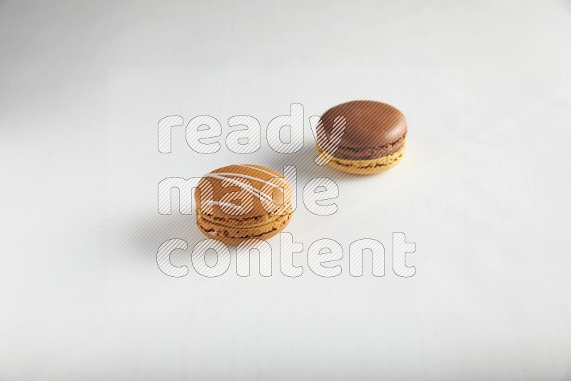 45º Shot of of two assorted Brown Irish Cream, and Yellow, and Brown Chai Latte macarons on white background