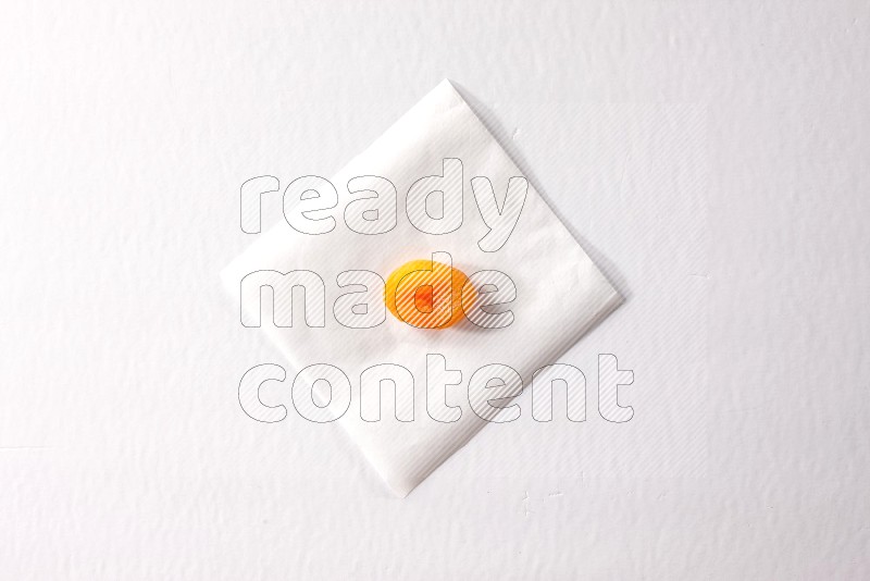 حبة واحدة من المشمش المجفف على قطعة من الورق على خلفية بيضاء