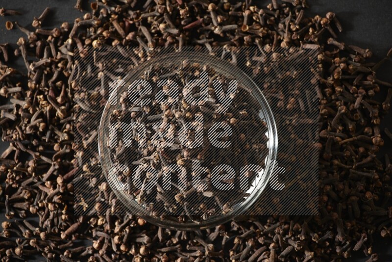 A glass bowl full of cloves on a black flooring