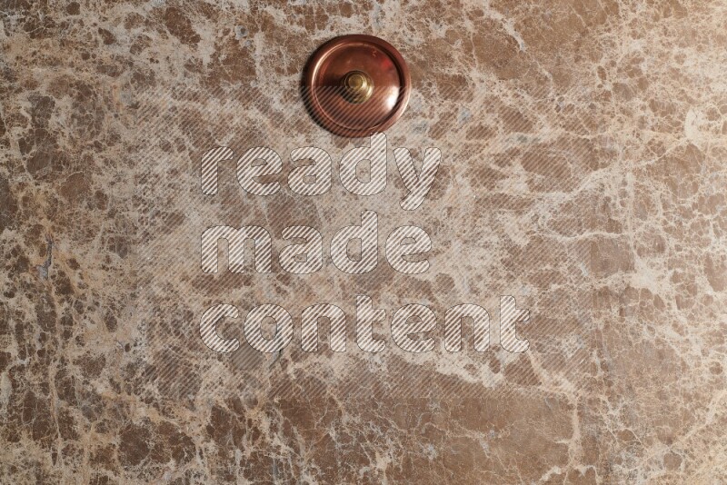 A small copper pot on beige marble background