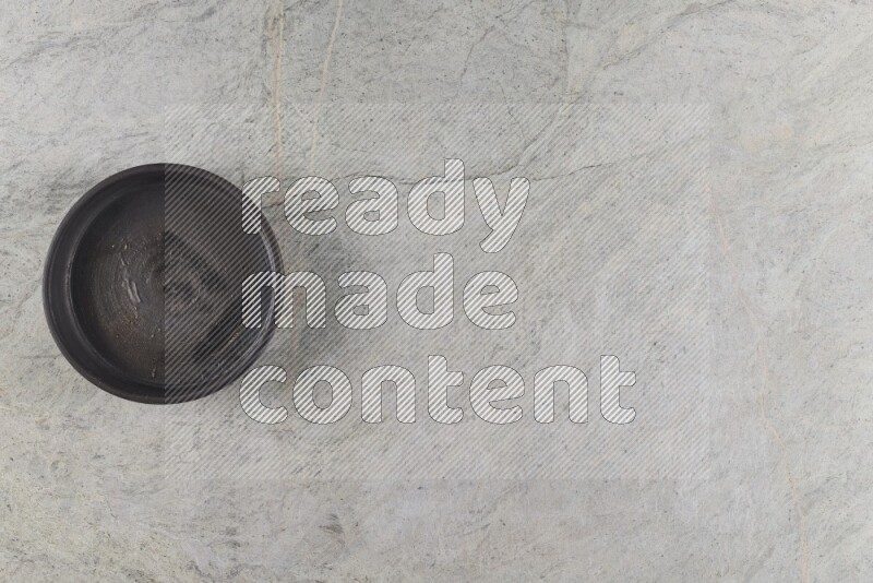 A black pottery oven bowl on grey marble background