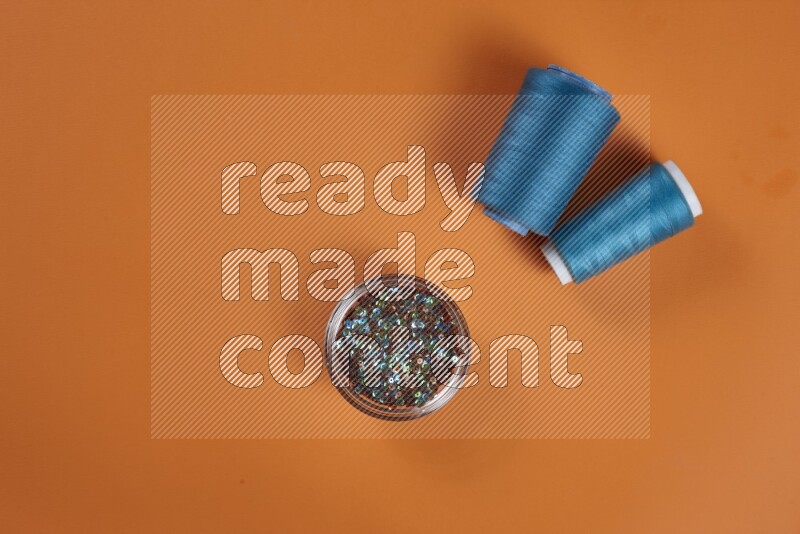 مجموعة من أدوات الخياطة والتفصيل زرقاء اللون على خلفية برتقالية