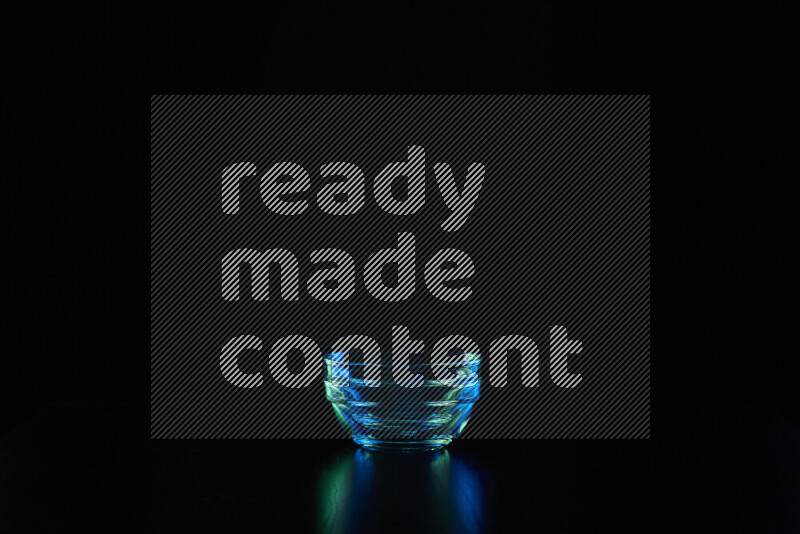 Glassware with rim light in blue and green against black background