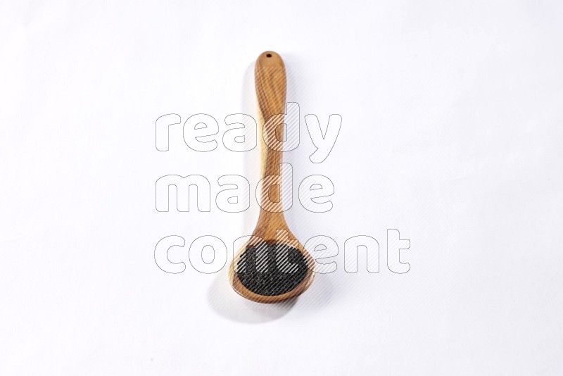 A wooden ladle full of black seeds on a white flooring in different angles