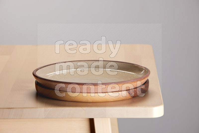 multi-colored pottery Plate placed on a light colored wooden tray on the edge of wooden table