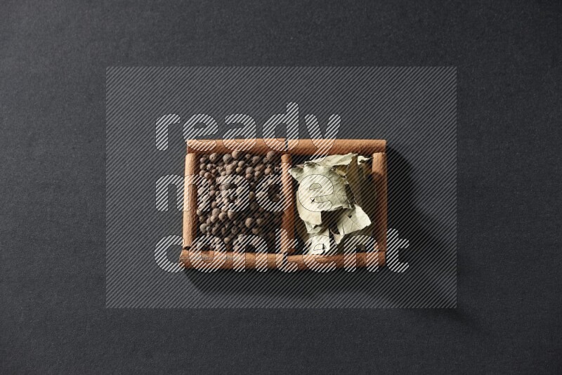 2 squares of cinnamon sticks full of allspice and bay laurel leaves on black flooring