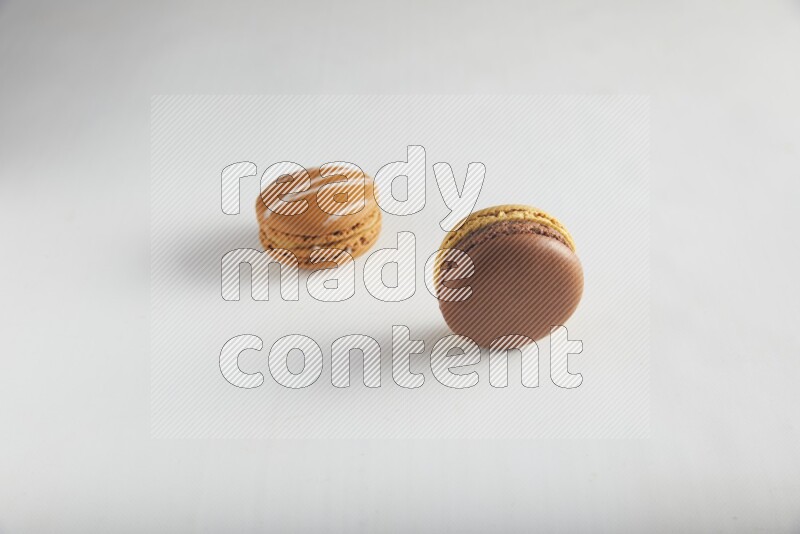 45º Shot of of two assorted Brown Irish Cream, and Yellow, and Brown Chai Latte macarons on white background