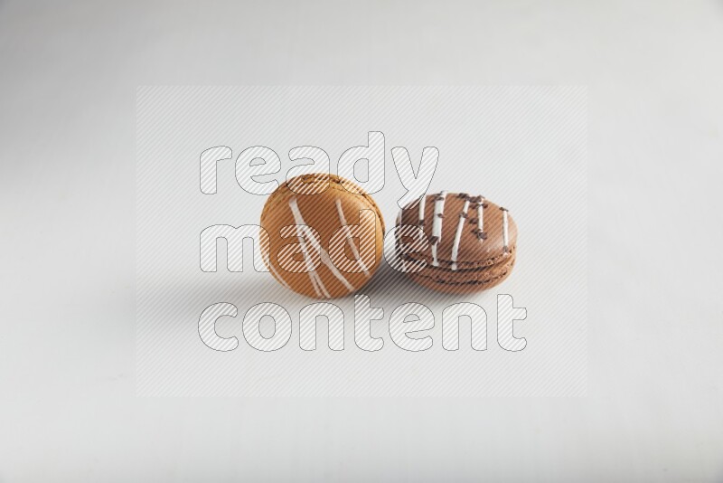 45º Shot of of two assorted Brown Irish Cream, and Brown white Chocolate Caramel macarons on white background