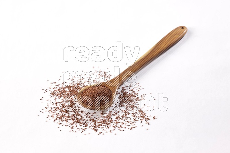 A wooden ladle full of garden cress seeds on a white flooring