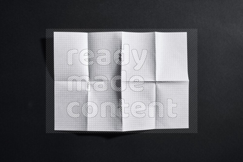 Folded notebook sheet on black background