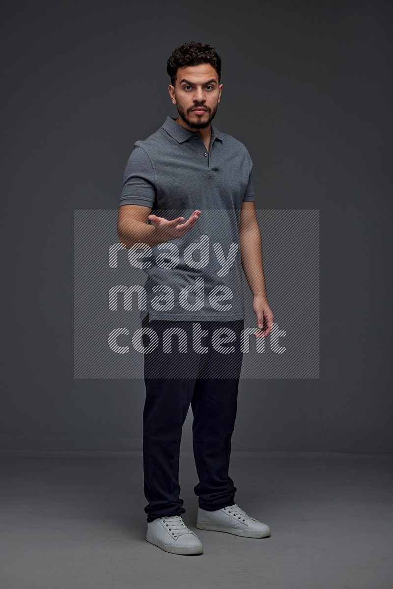 A man wearing casual standing and making multi hand gestures eye level on a gray background