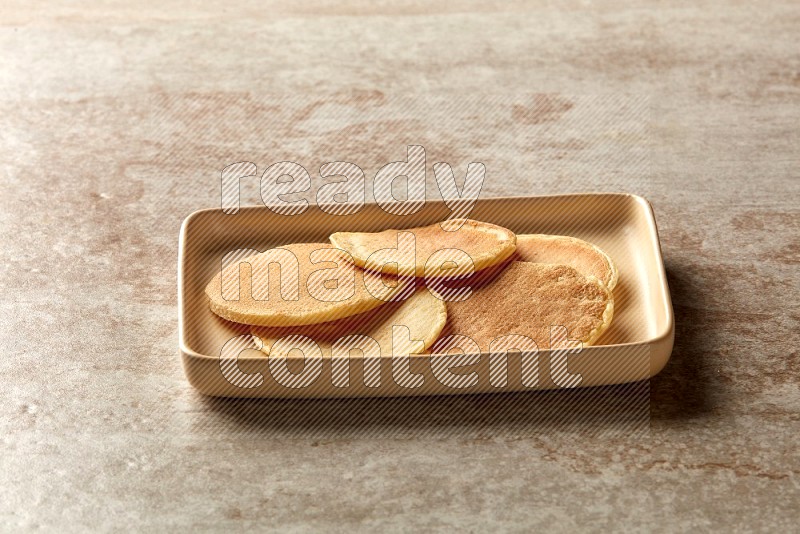 Five stacked plain mini pancakes in a rectangular plate on beige background