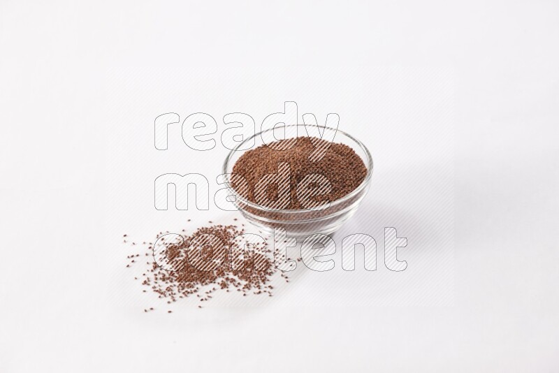 A glass bowl full of garden cress seeds with more seeds spread on a white flooring