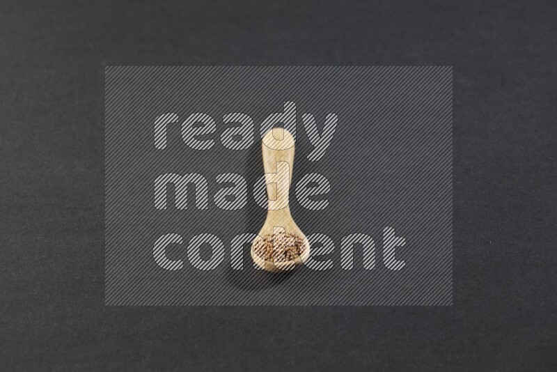 ملعقة خشبية ممتلئة ببذور الخردل علي خلفية سوداء