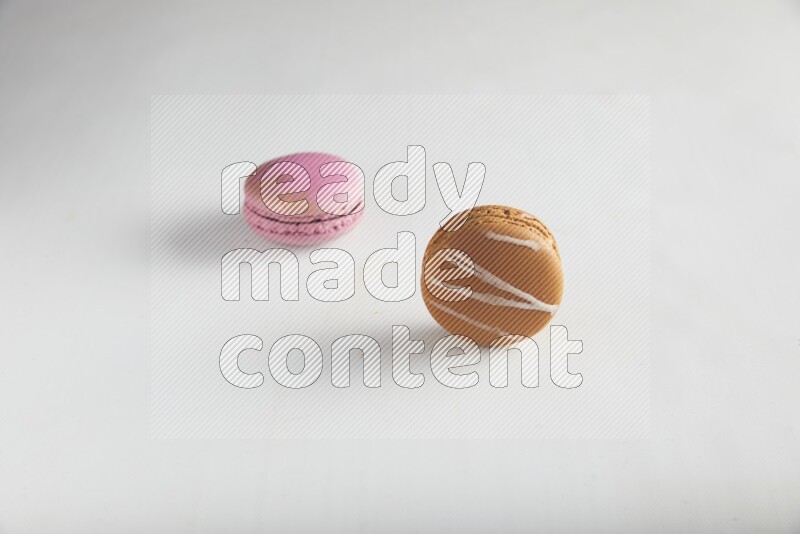 45º Shot of of two assorted Brown Irish Cream, and Purple Strawberry macarons on white background