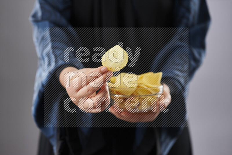 Woman in abaya holding different kinds of snacks in different positions