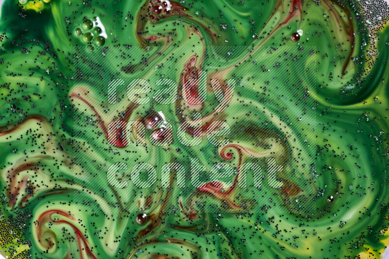 A close-up of sparkling green glitter scattered on swirling green and red background