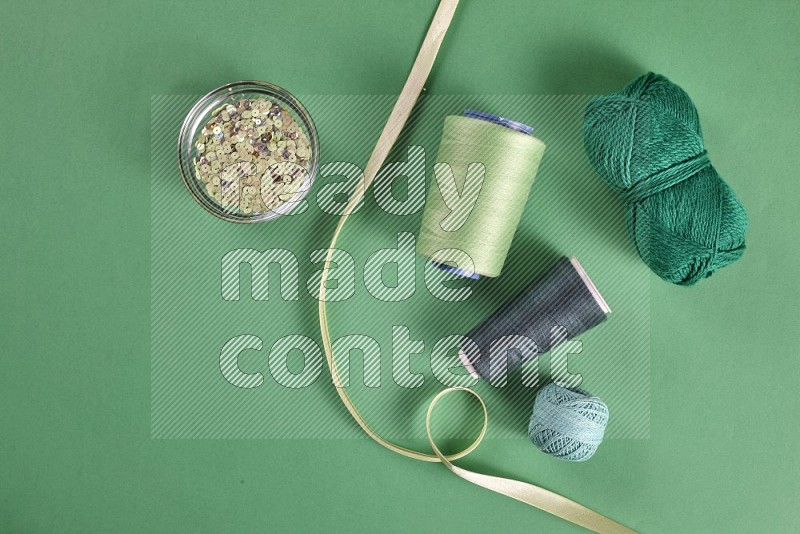 Green sewing supplies on green background
