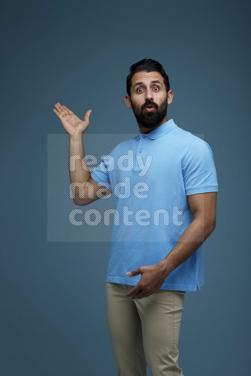 A man pointing  in a blue background wearing a Blue shirt