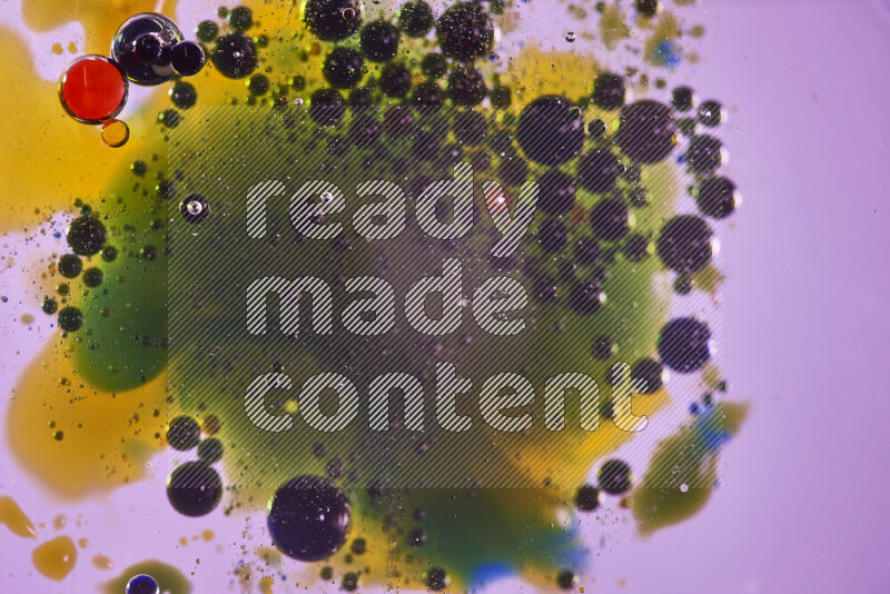 Close-ups of abstract red, blue, yellow and green watercolor drops on oil Surface on pink background